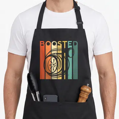 Turbo auto apron - BOOSTED text in orange yellow teal grey vertical stripes with grey turbocharger drawing — shown on a black cotton canvas apron against a white background