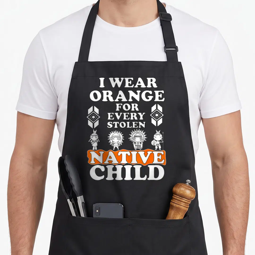 Vintage pride native american apron - Text I Wear Orange For Every Stolen Native Child with four cartoon children — shown on a black cotton canvas apron against a white background