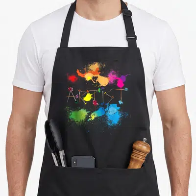 Messy painter apron - Paintbrushes arranged to spell ARTIST surrounded by colorful paint splatters — shown on a black cotton canvas apron against a white background