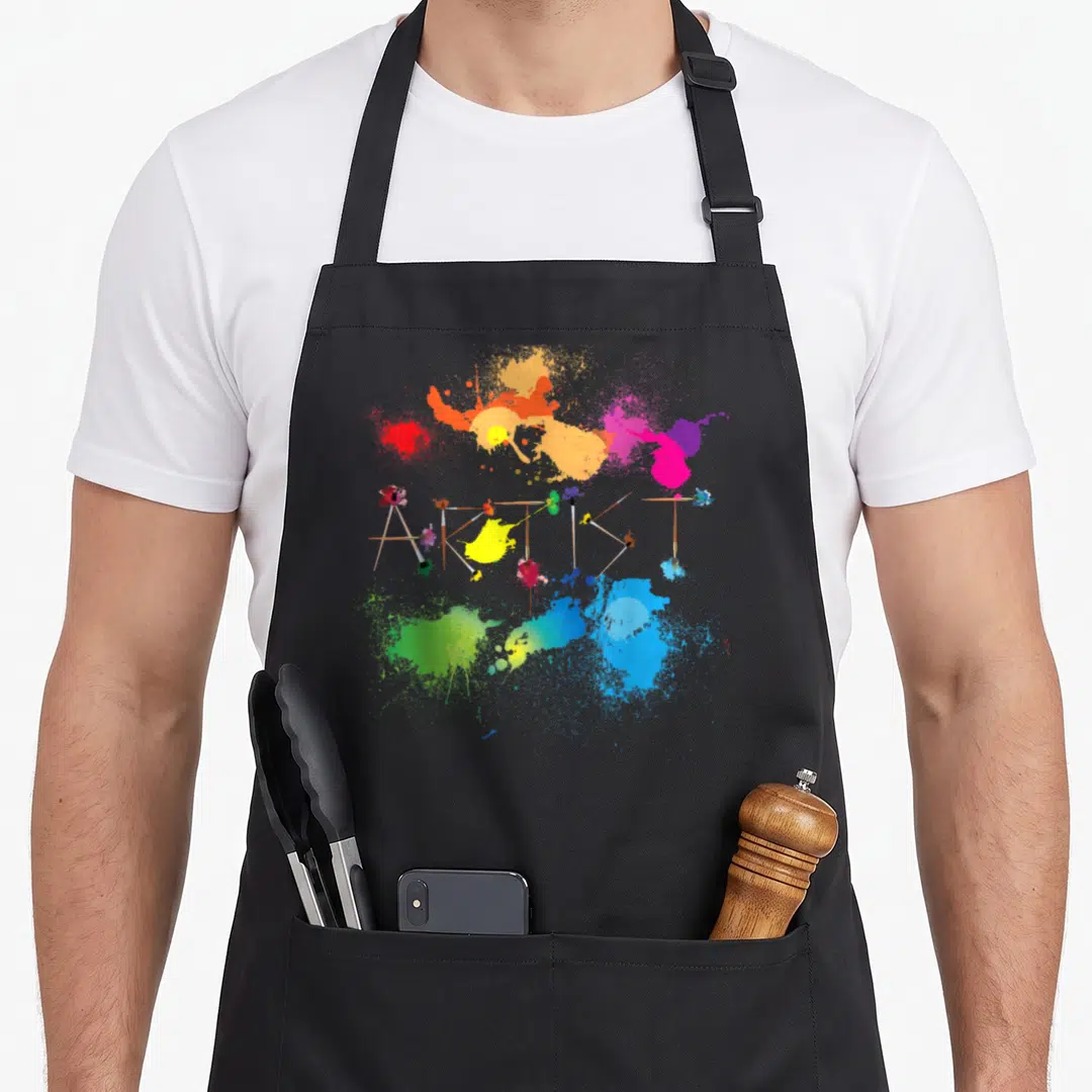 Messy painter apron - Paintbrushes arranged to spell ARTIST surrounded by colorful paint splatters — shown on a black cotton canvas apron against a white background