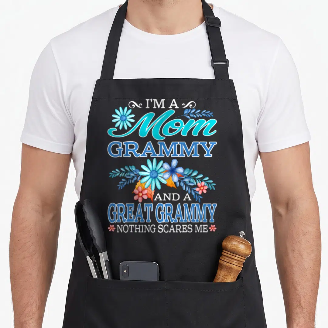 Scare grammy apron - Teal and blue text reading Mom Grammy Great Grammy with pink and blue flowers — shown on a black cotton canvas apron against a white background
