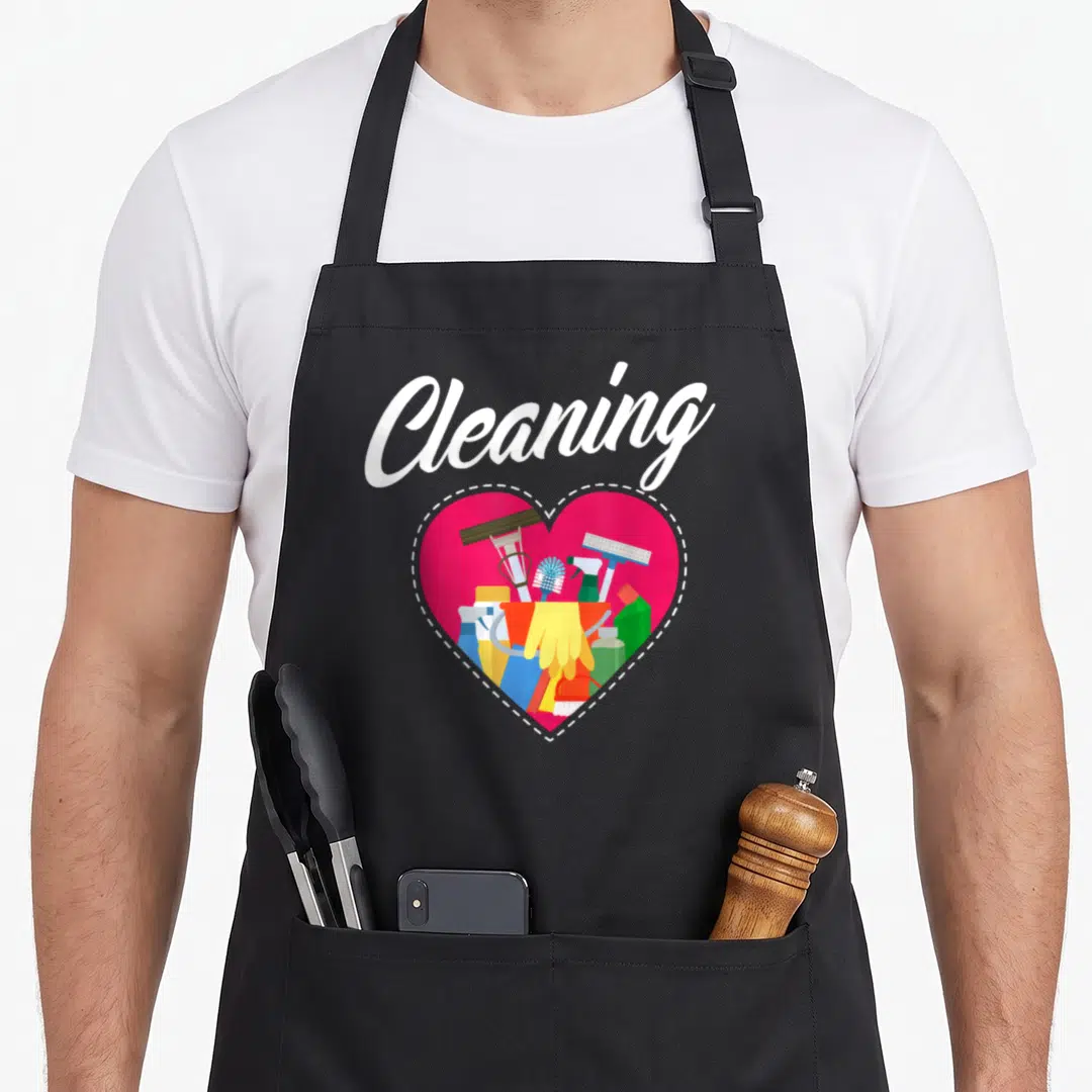 Cute cleaning housekeeper apron - Pink heart outline filled with spray bottles, squeegee, and yellow gloves under white — shown on a black cotton canvas apron against a white background