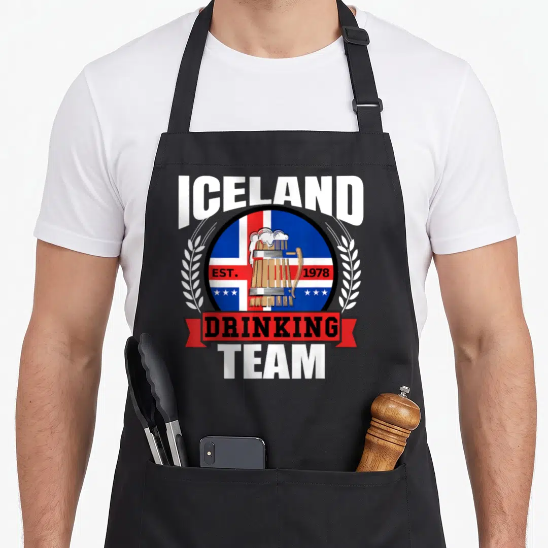 Iceland beer apron - Beer mug on Iceland flag circle with Drinking Team text and wheat stalks in blue red white gold — shown on a black cotton canvas apron against a white background