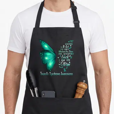 Tourette butterfly apron - Teal butterfly with I Am The Storm quote and awareness ribbon hearts — shown on a black cotton canvas apron against a white background