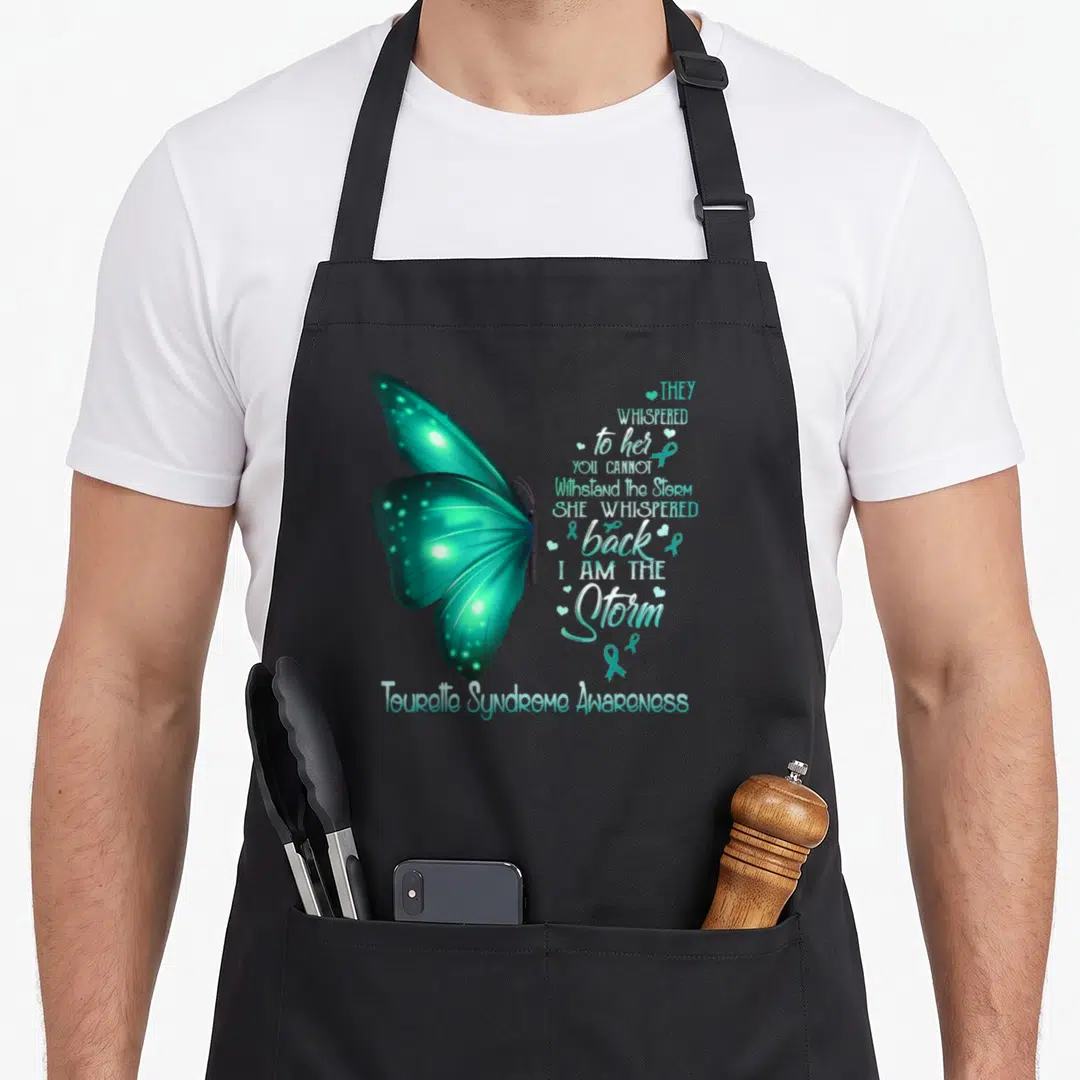 Tourette butterfly apron - Teal butterfly with I Am The Storm quote and awareness ribbon hearts — shown on a black cotton canvas apron against a white background