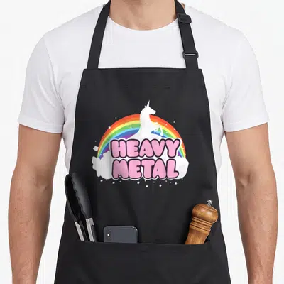 Ella heavy metal apron - Pink HEAVY METAL text over white unicorn and rainbow with stars — shown on a black cotton canvas apron against a white background