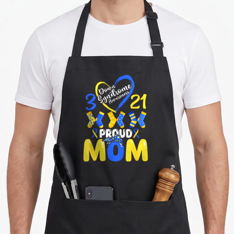 Syndrome mom daughter apron - Blue yellow heart with Down Syndrome Awareness text, three socks, and Proud Mom lettering — shown on a black cotton canvas apron against a white background