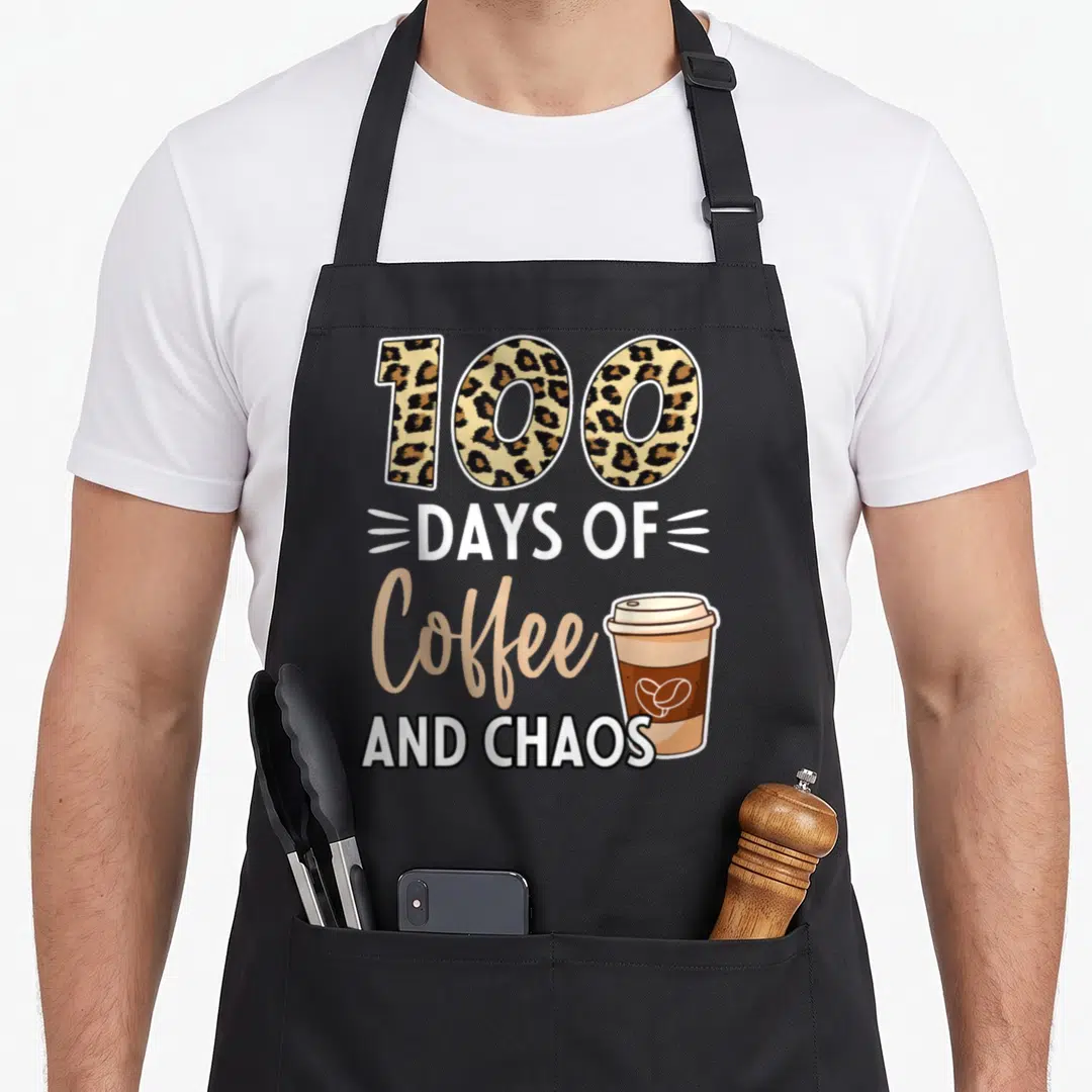 Coffee chao teacher apron - Leopard print 100, days of coffee and chaos text, and a brown takeaway coffee cup — shown on a black cotton canvas apron against a white background
