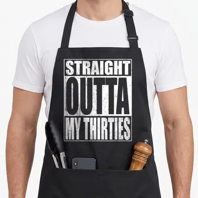 Straight 40th birthday apron - White distressed text reading STRAIGHT OUTTA MY THIRTIES stacked in a rectangle — shown on a black cotton canvas apron against a white background