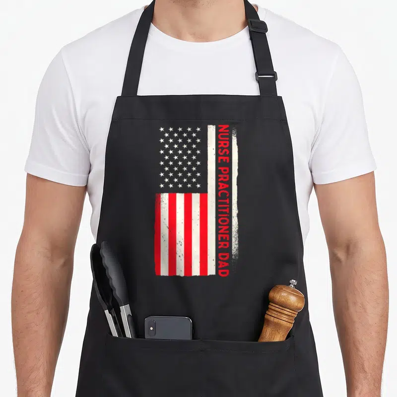 Patriotic doctor with apron - Vertical USA flag with distressed red NURSE PRACTITIONER DAD text overlapping stripes — shown on a black cotton canvas apron against a white background
