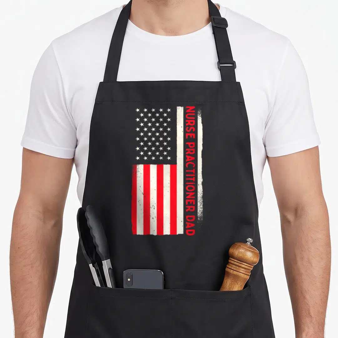 Patriotic doctor with apron - Vertical USA flag with distressed red NURSE PRACTITIONER DAD text overlapping stripes — shown on a black cotton canvas apron against a white background