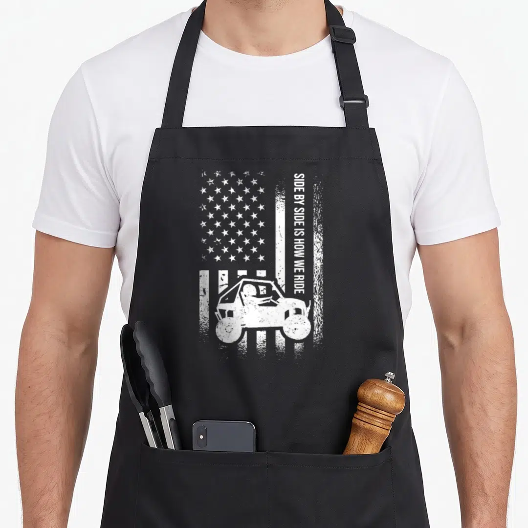 Ride american flag apron - Distressed white USA flag background with vertical text and UTV silhouette — shown on a black cotton canvas apron against a white background