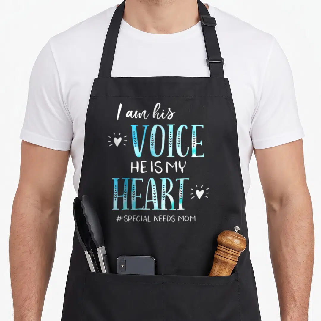 Autism special aprons - Stacked blue and white text I am his Voice He Is My Heart with radiating hearts — shown on a black cotton canvas apron against a white background