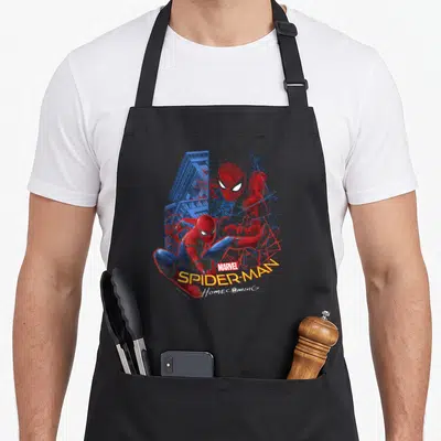 Friendly homecoming apron - Two Spider-Man figures in red blue yellow with MARVEL SPIDER-MAN Homecoming text — shown on a black cotton canvas apron against a white background