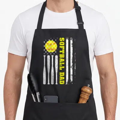 Softball father day apron - Vertical SOFTBALL DAD text in distressed yellow beside white bat stripes and a yellow — shown on a black cotton canvas apron against a white background