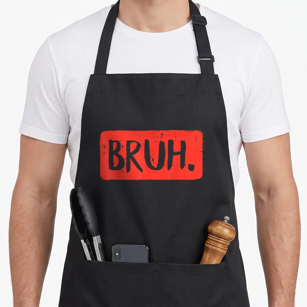 Bruh meme apron - Grey BRUH text inside a red distressed rectangular block — shown on a black cotton canvas apron against a white background