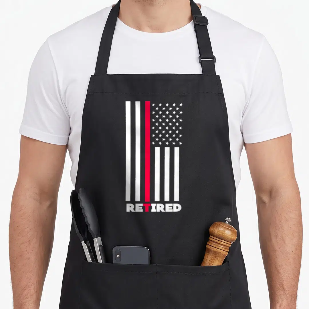 Thin line firefighter cooking apron - Vertical white and red flag stripes above the word RETIRED in white block letters — shown on a black cotton canvas apron against a white background