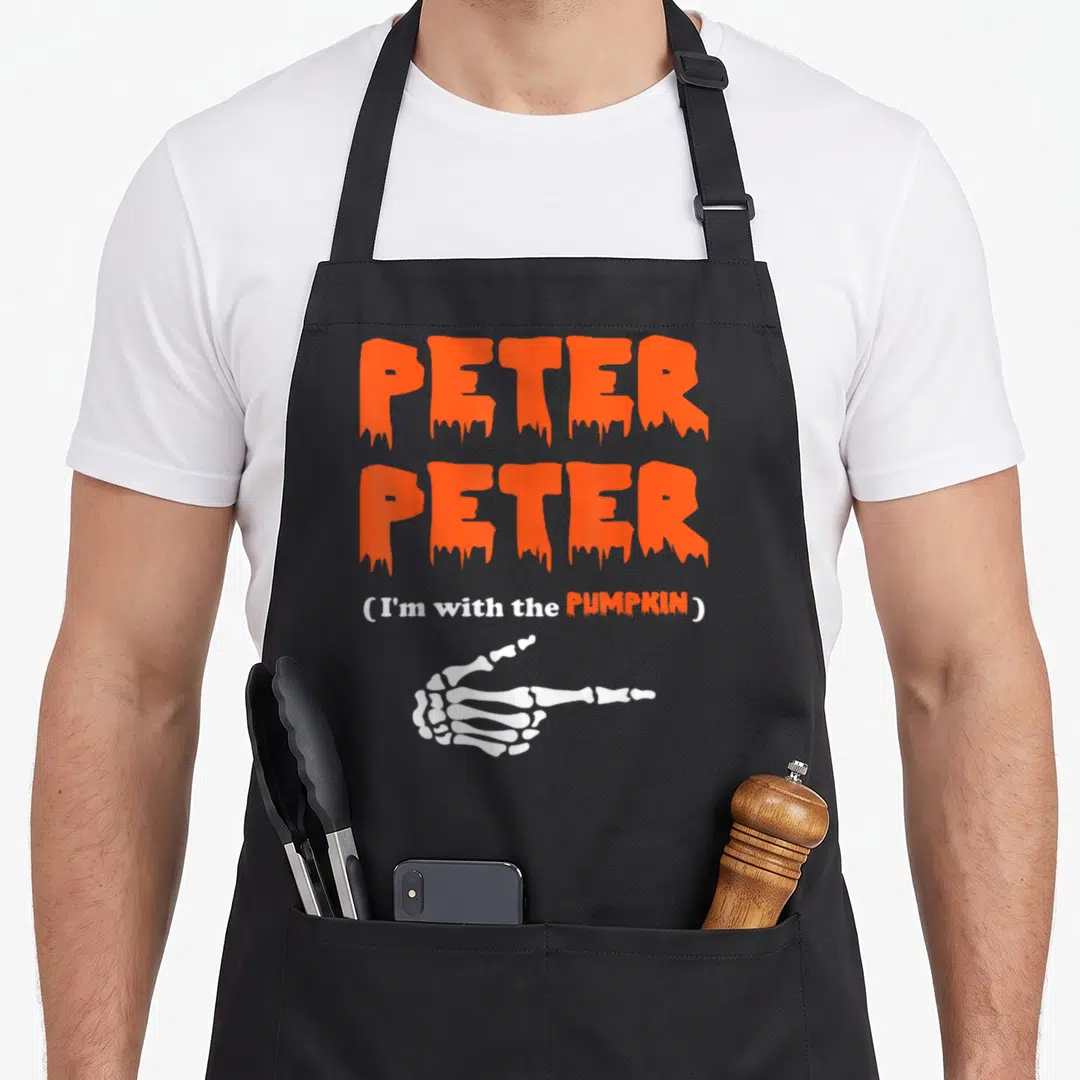 Peter halloween kitchen aprons - Orange dripping text PETER PETER above white skeleton hand pointing right — shown on a black cotton canvas apron against a white background