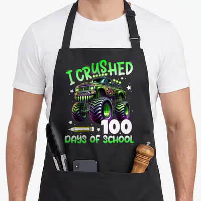 100th truck apron - I Crushed 100 Days of School monster truck with pencil and stars in green purple white yellow — shown on a black cotton canvas apron against a white background