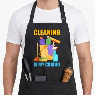Cardio cleaning apron - Cartoon bucket with purple gloves, orange plunger, and spray bottles under bold text — shown on a black cotton canvas apron against a white background