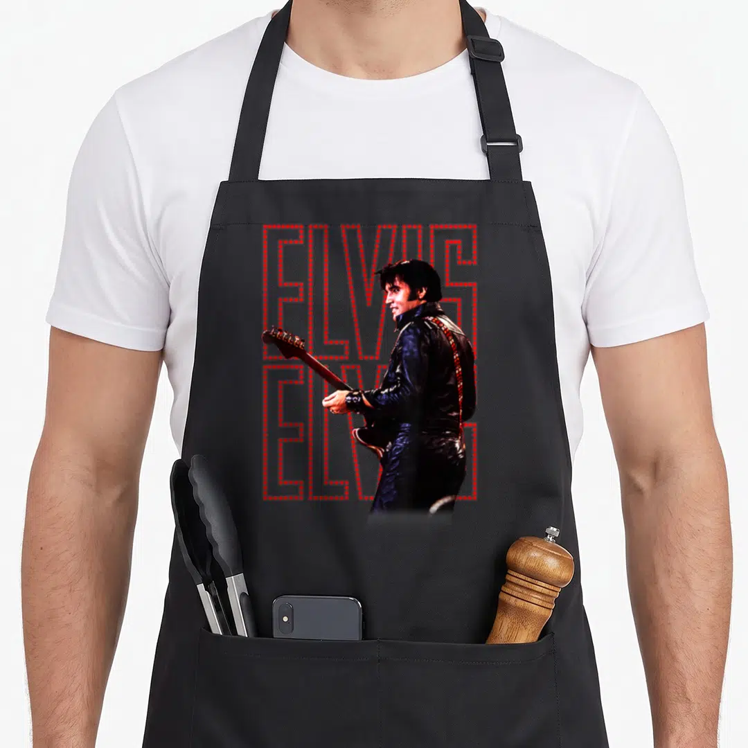 Elvis special aprons - Vertical stack of red dots spelling ELVIS behind photo of singer in black leather jacket holding — shown on a black cotton canvas apron against a white background