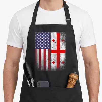 Georgia american flag apron - Distressed USA and Georgia flags side by side in red white blue — shown on a black cotton canvas apron against a white background