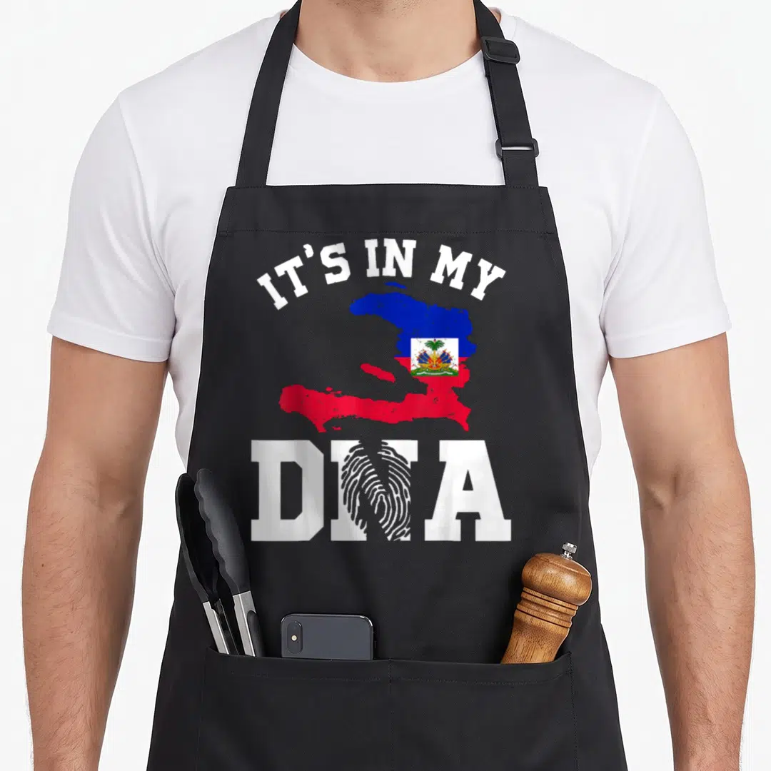 Haiti pride apron - IT'S IN MY DNA text with Haiti flag map and fingerprint N lettering — shown on a black cotton canvas apron against a white background