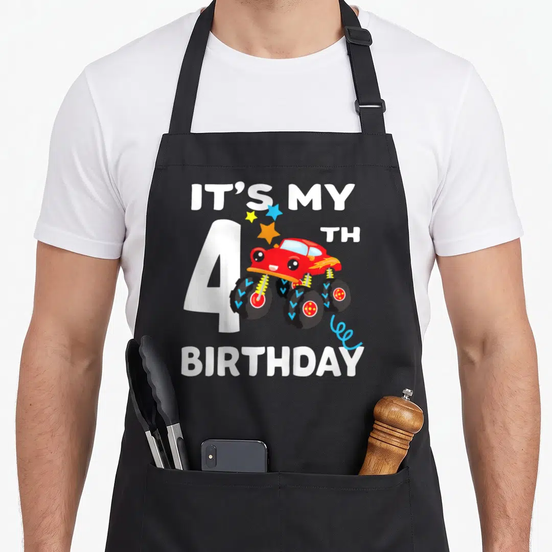 4yr truck apron - Red monster truck with IT'S MY 4TH BIRTHDAY text and white number 4 — shown on a black cotton canvas apron against a white background