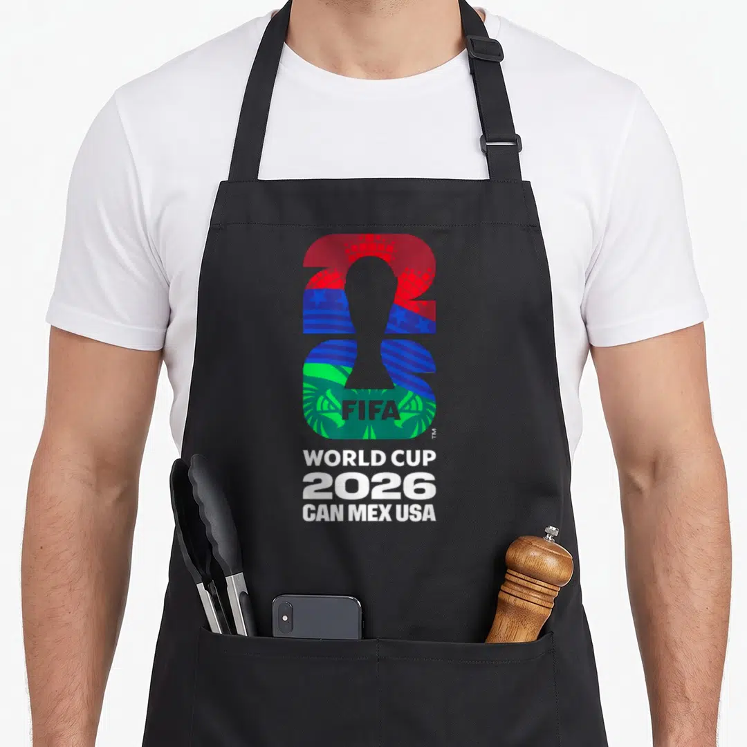 Host country apron - Grey trophy silhouette inside colorful 2026 digits with stacked white text — shown on a black cotton canvas apron against a white background