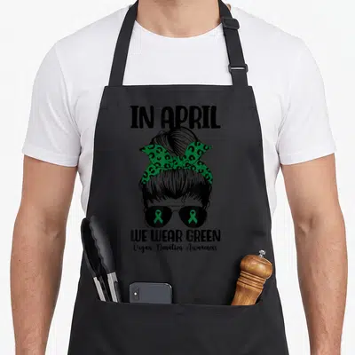 Messy organ apron - Black line-art woman with green leopard bandana and green ribbons in sunglasses lenses — shown on a black cotton canvas apron against a white background