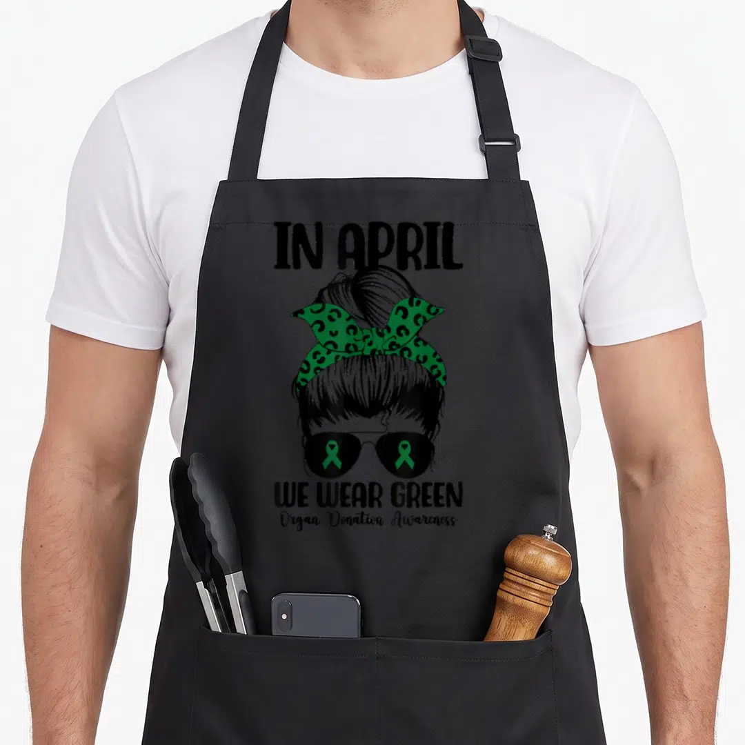 Messy organ apron - Black line-art woman with green leopard bandana and green ribbons in sunglasses lenses — shown on a black cotton canvas apron against a white background