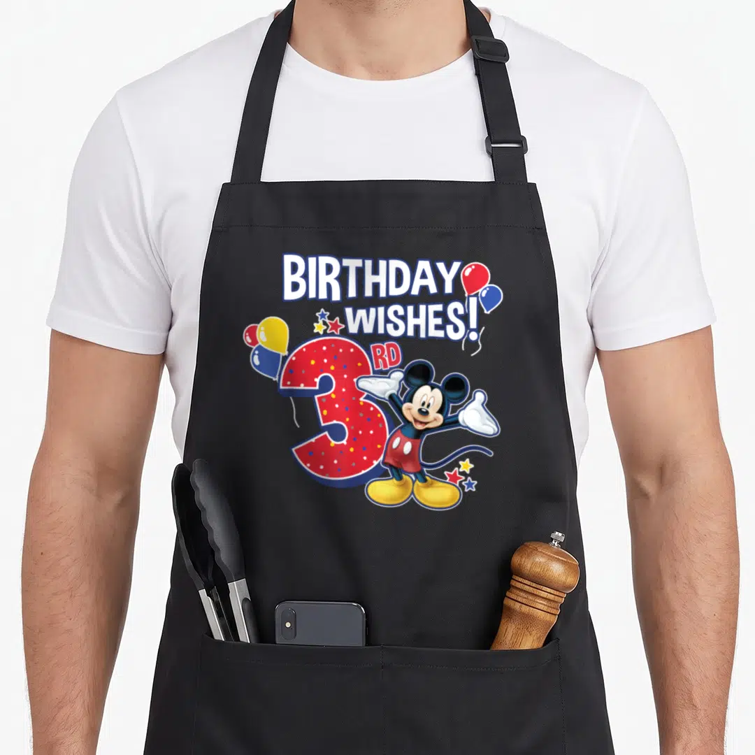 3rd friends apron - Mickey Mouse beside red polka-dotted number 3 with balloons and BIRTHDAY WISHES text — shown on a black cotton canvas apron against a white background