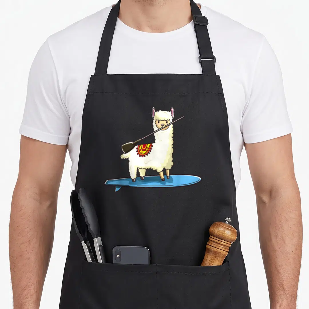 Paddleboarding paddle apron - Cartoon white llama on blue surfboard holding paddle with red and yellow blanket — shown on a black cotton canvas apron against a white background