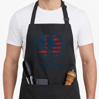 Honoring american flag apron - Soldier silhouette against flag with HONORING ALL WHO SERVED Thank You VETERANS text — shown on a black cotton canvas apron against a white background