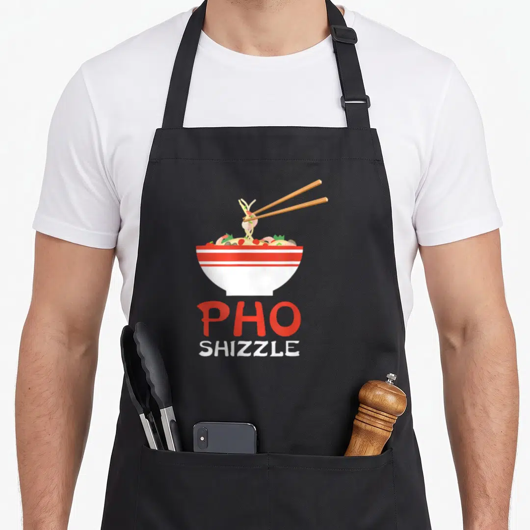 Hop pho apron - Cartoon pho bowl with chopsticks and red white stacked text — shown on a black cotton canvas apron against a white background
