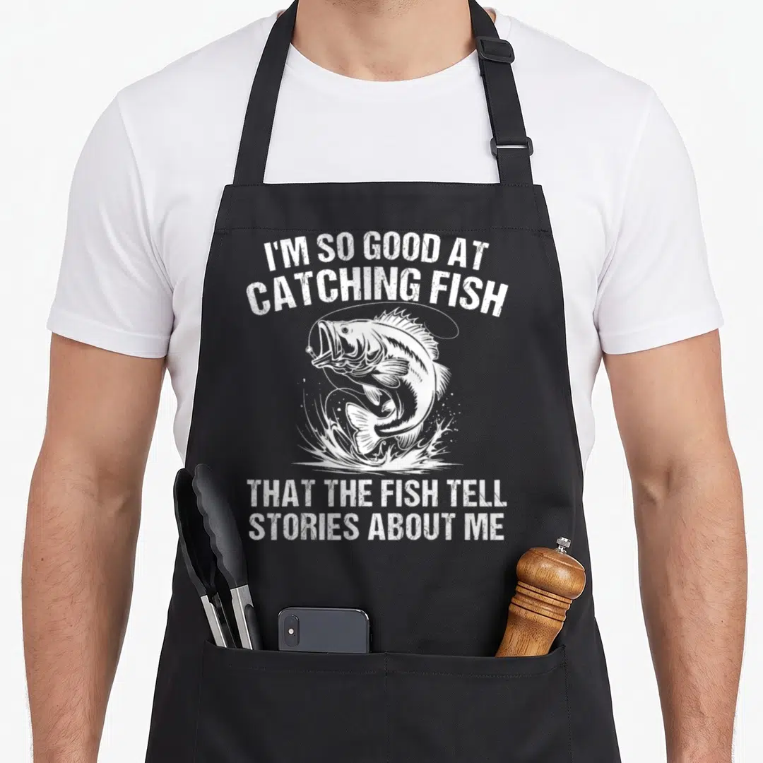 Catch fishing aprons - White distressed text and leaping fish graphic with sarcastic fishing quote — shown on a black cotton canvas apron against a white background