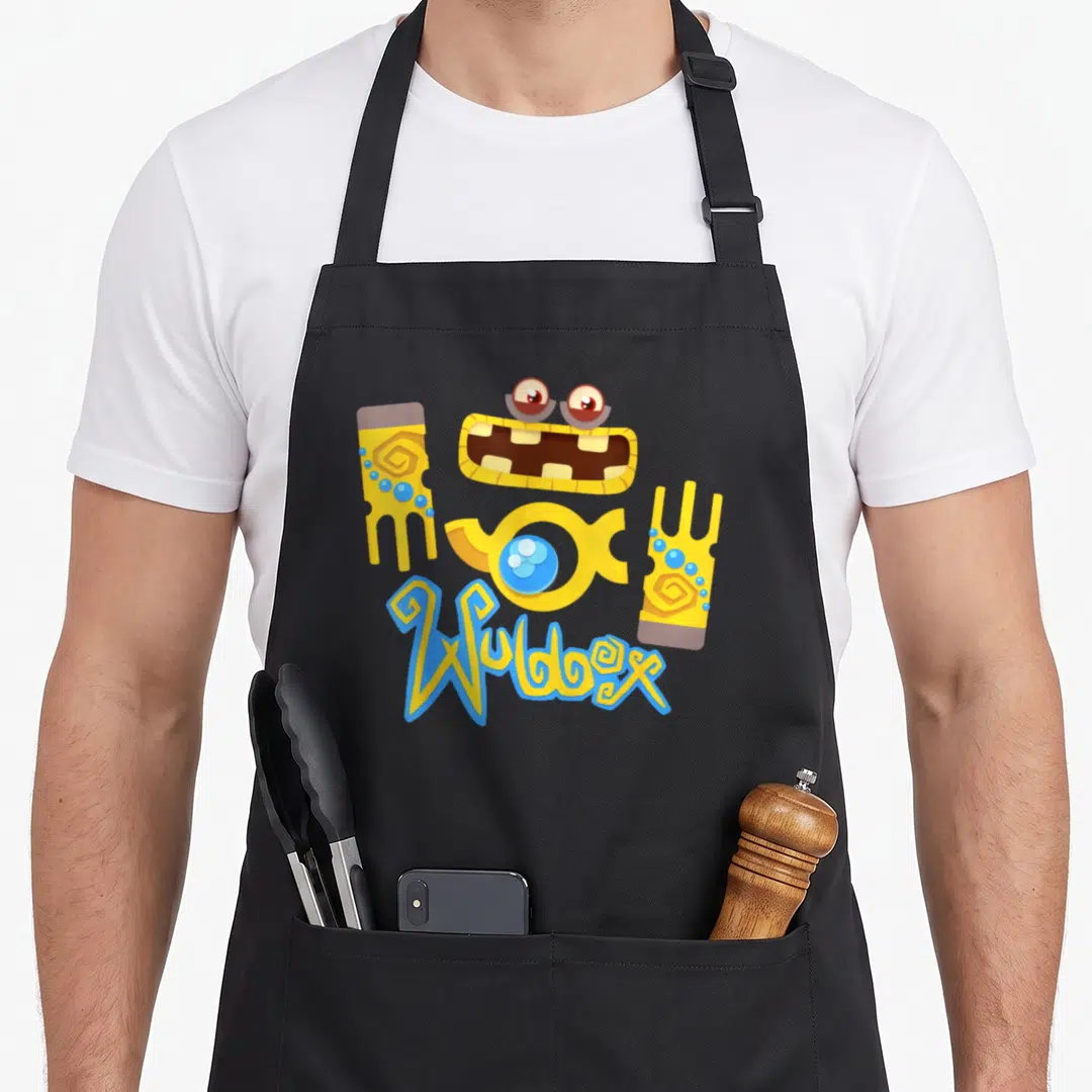 Singing boy monster apron - Scattered yellow Wubbox monster parts with blue text Wubbox below — shown on a black cotton canvas apron against a white background