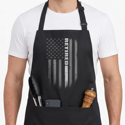 Retired corrections officer apron - Vertical distressed USA flag with grey stripes and white RETIRED text overlay — shown on a black cotton canvas apron against a white background