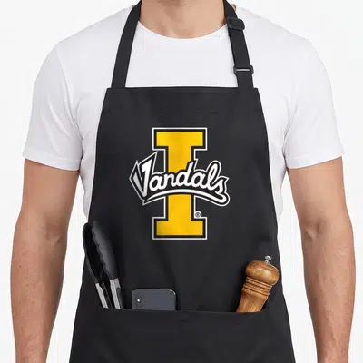 Idaho lakeland apron - Yellow I letter with Vandals white script and black outline — shown on a black cotton canvas apron against a white background