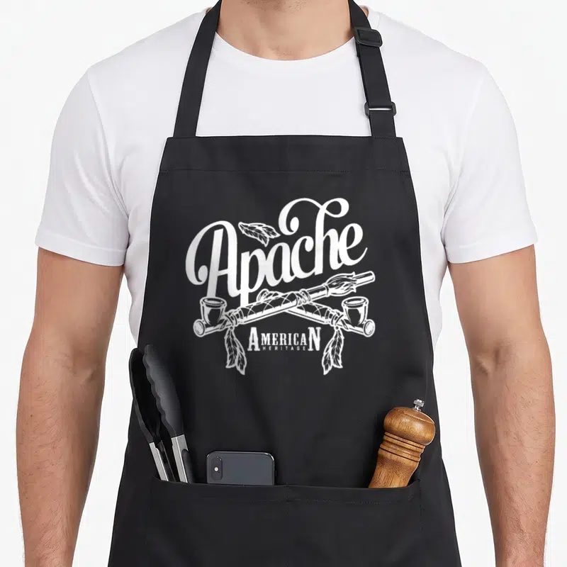 Apache native american aprons - White line art of crossed peace pipes and feathers with text Apache American Heritage — shown on a black cotton canvas apron against a white background