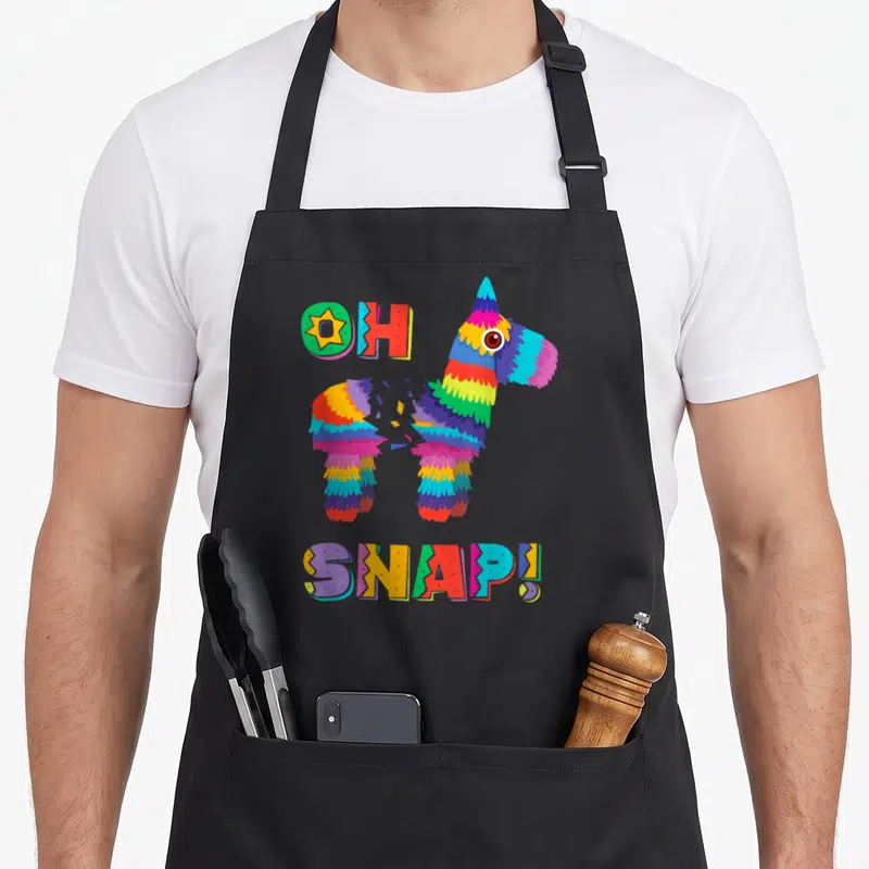 Pinata mexican apron - Cartoon piñata splitting in middle with OH SNAP! text in blue red yellow green purple — shown on a black cotton canvas apron against a white background