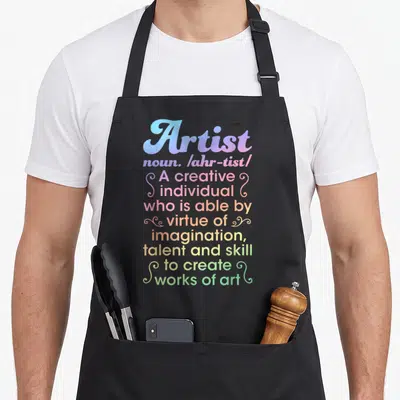 Artist creative apron - Stacked colorful dictionary definition text reading Artist noun creative individual works of art — shown on a black cotton canvas apron against a white background