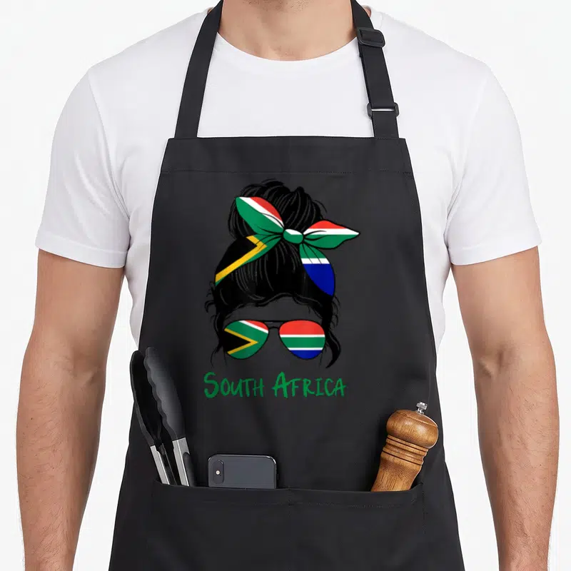 Flag south african apron - Woman bun sunglasses ribbon green red yellow blue black SOUTH AFRICA text — shown on a black cotton canvas apron against a white background