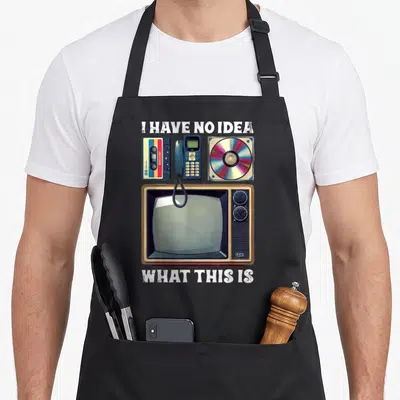 90s theme chef outfit with apron - Retro cassette tape, corded phone, CD case, and CRT television with distressed white — shown on a black cotton canvas apron against a white background