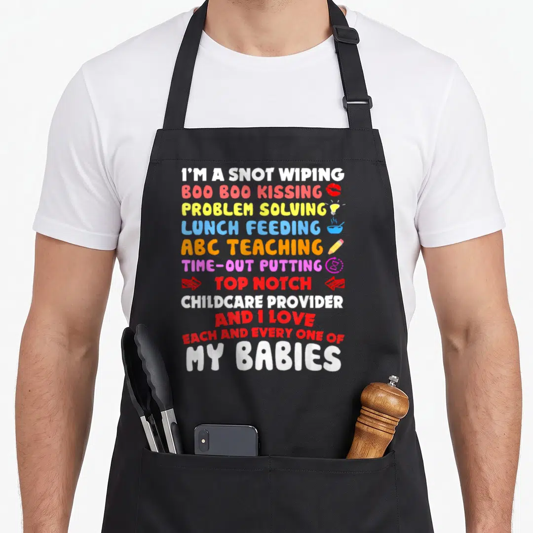 Notch teacher apron - Stacked colorful text reading I'm a snot wiping boo boo kissing top notch childcare provider — shown on a black cotton canvas apron against a white background