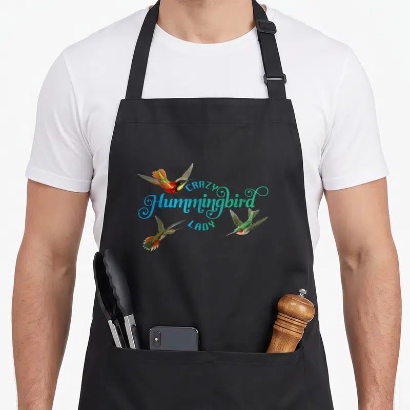 Vintage hummingbird bird apron - Three realistic hummingbirds in blue green red surrounding centered text — shown on a black cotton canvas apron against a white background