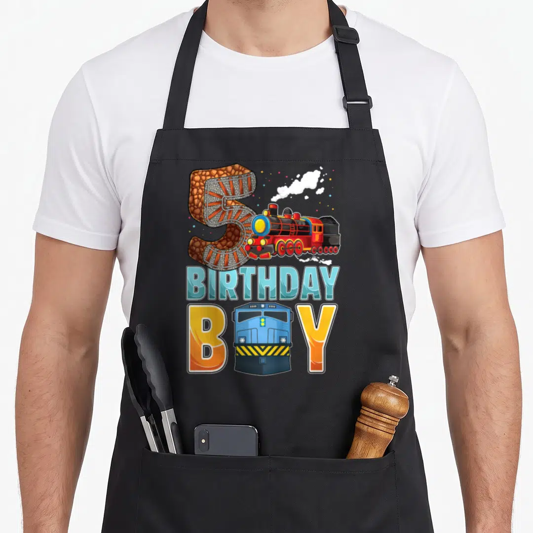 Railroad 5th birthday apron - Number 5 track texture, red steam train, blue locomotive replacing letter O, text — shown on a black cotton canvas apron against a white background