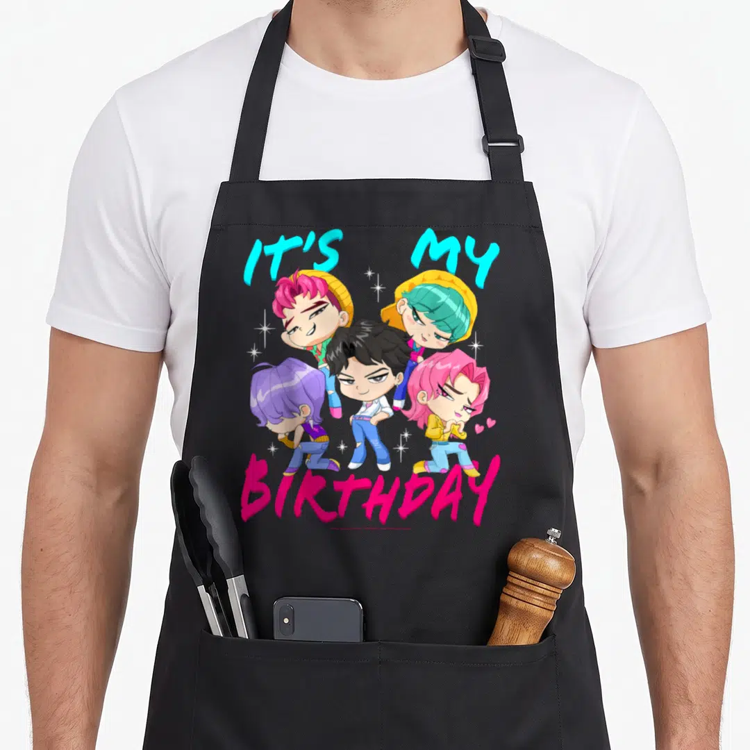 Birthday hunter apron - Four cartoon characters with IT'S MY BIRTHDAY text and sparkles in cyan magenta yellow purple — shown on a black cotton canvas apron against a white background