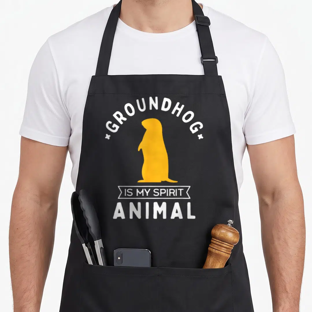 Groundhog animal apron - Yellow groundhog silhouette with white text GROUNDHOG IS MY SPIRIT ANIMAL — shown on a black cotton canvas apron against a white background