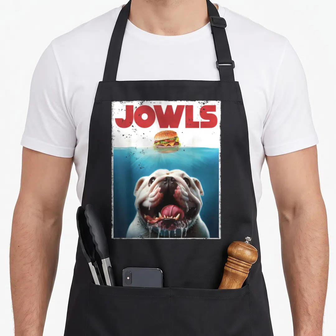 Jowl english aprons - Red JOWLS text above bulldog in blue water chasing floating burger — shown on a black cotton canvas apron against a white background